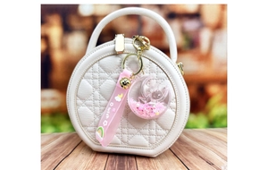 Detail of pink moon rabbit keychain with floating glitter on a white quilted bag