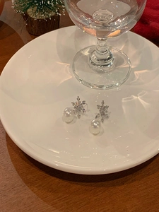 Détail des boucles d'oreilles flocon de neige en argent avec zircone et perle sur céramique
