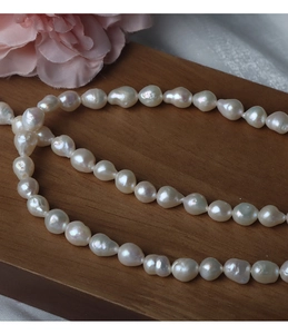 Macro shot of 6.5-7mm irregular baroque freshwater pearls on a dark wooden tray