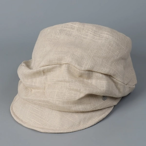 Detailed close-up of light beige linen newsboy cap showing natural woven texture and metal tag