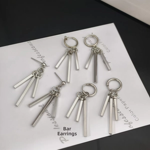 Macro detail of silver geometric square bar pendants on industrial style steel earrings