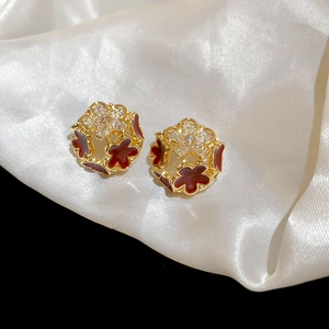Detailed macro view of golden hollow floral beads with red enamel and zircon stones