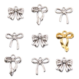 Detailed view of assorted silver and gold alloy bow pendants for DIY jewelry making