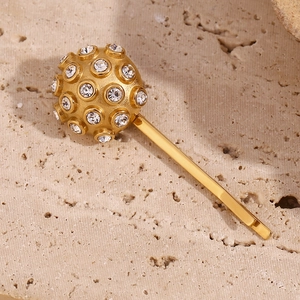Detailed view of an 18K gold-plated hair clip with a sparkling white rhinestone sphere