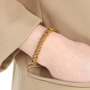 Dettaglio del bracciale a catena ritorta in stile punk dorato al polso con finitura lucida