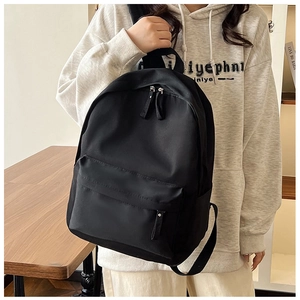 Classic black high-capacity backpack with front zipper pocket held by a model