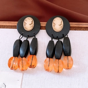 Macro detail of vintage cameo drop earrings with black beads and amber resin spheres