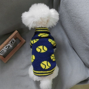 Detail of navy blue knitted pet sweater with yellow tennis pattern on a white dog