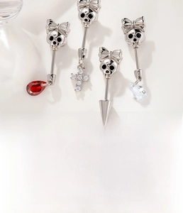 Detailed macro view of silver bow-knot skull ear piercings with zircon and cross pendants