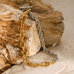 Macro detail of two-tone stainless steel mixed chain link bracelet on natural rock