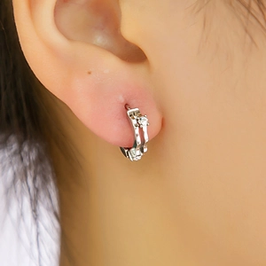 Gros plan d'une boucle d'oreille anneau argentée avec zircons blancs portée à l'oreille