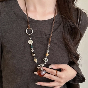 Close-up of heart pendant necklace with vintage ceramic beads on a woven brown cord
