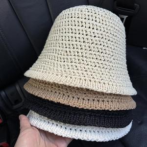 Close-up of four stacked knit bucket hats in beige, khaki, black and white showing mesh texture