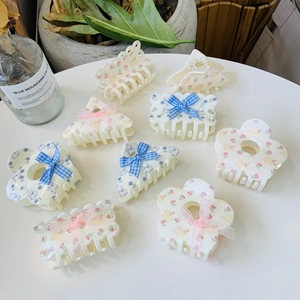 Flat lay of multiple floral acrylic hair clips with ribbons and rabbit prints on white desk