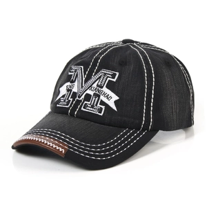 Detailed view of grey denim baseball cap with letter M embroidery and leather brim trim