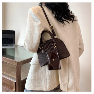 Detail of dark brown croc-effect shell bag featuring a mini pouch and adjustable strap