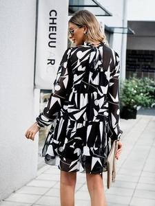 Détail de robe à imprimé géométrique noir et blanc avec jupe à volants et nœud au cou