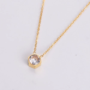 Macro detail of gold hexagon pendant featuring a centered sparkling round zircon stone