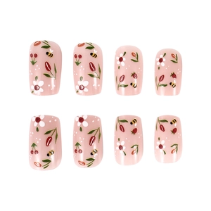 Detailed close-up of light pink press-on nails with hand-painted floral and cherry motifs