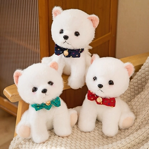 Three white plush Pomeranian puppy dolls wearing colorful polka dot bow ties on a chair
