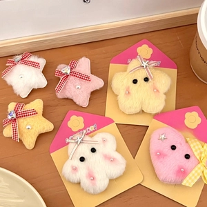 Detail of plush star hair clips with plaid bows and pearls on a yellow display card