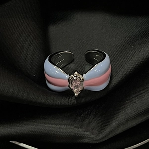 Detail of a french style open ring featuring a pink teardrop gemstone and blue enamel stripes