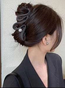 S-shaped black shark hair clip with white pearl detail shown on model's head