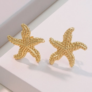 Golden starfish stud earrings with textured surface on minimalist white geometric stand