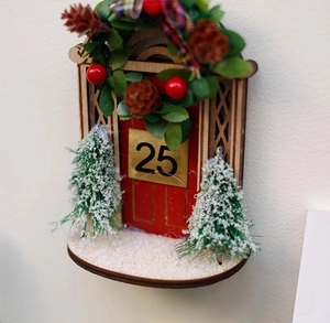 Wooden Christmas door ornament with miniature snowy trees and a red number 25 plaque