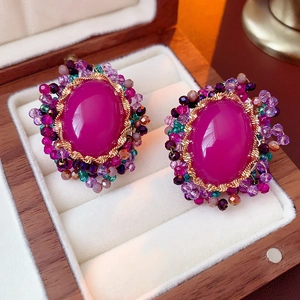 Macro view of vintage gold stud earrings with oval magenta gemstone and colorful beads