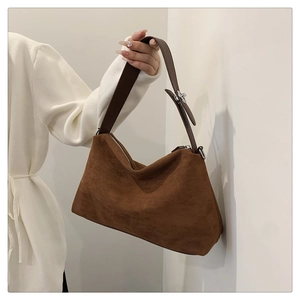 Détail de la texture en daim et boucle argentée sur le sac bandoulière marron foncé