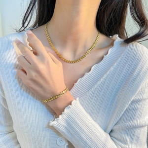 Minimalist gold heart stainless steel necklace and bracelet set shown on a female model