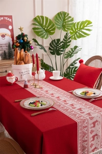 Detailed top view of red jacquard Christmas tablecloth with deer and tree woven runner