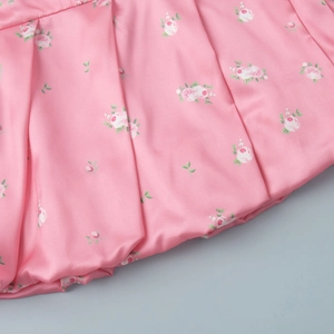 Close-up of pink floral satin fabric with pleated details and elegant rose prints