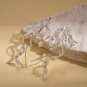 Detailed shot of silver irregular branch earrings with white teardrop pearls on a stone