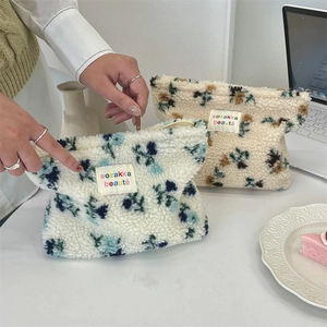 Macro view of plush floral cosmetic bags with soft fleece texture and zipper closure