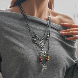Détail d'un collier bohème multicouche avec pendentifs fleuris et perles colorées