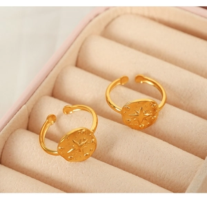 Detailed view of adjustable gold-plated rings with starburst embossing in a pink gift box