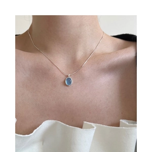 Detail of oval aquamarine pendant on a silver chain worn on the collarbone