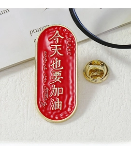 Close-up of red enamel lucky charm brooch with gold text for student graduation gift