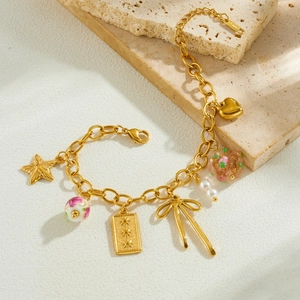 Bracelet doré à breloques avec étoiles, perles et nœuds sur un support en pierre texturé