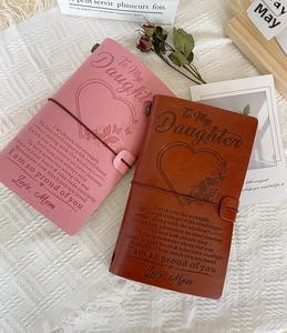 Detail of leather journals with 'To My Daughter' engraving in pink and brown tones