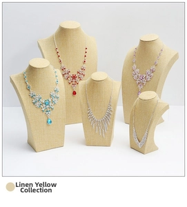 Linen yellow mannequin neck stands displaying sparkling rhinestone necklaces in various colors