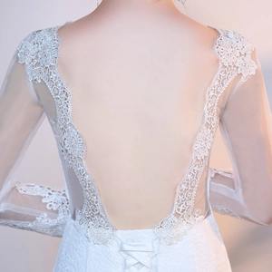 Close-up of deep V backless lace wedding dress with sheer sleeves and silk waist tie