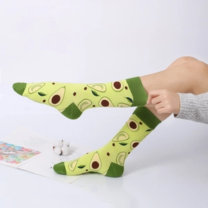 Creative avocado pattern crew socks in green cotton knit worn by a model in a studio