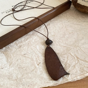 Detail of vintage wooden pendant necklace on a natural coconut shell and art paper background