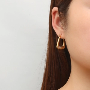 Textured 18K gold triangle earrings for women on model side profile with a modern finish