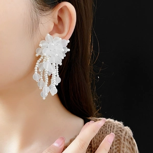 Eleganti orecchini a fiore con perle bianche e nappe indossati da una modella