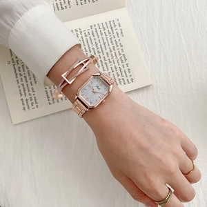 Close-up of rose gold square watch paired with geometric bracelet and rings