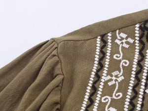Détail de la blouse vert olive avec broderies noires et blanches et texture en coton tissé